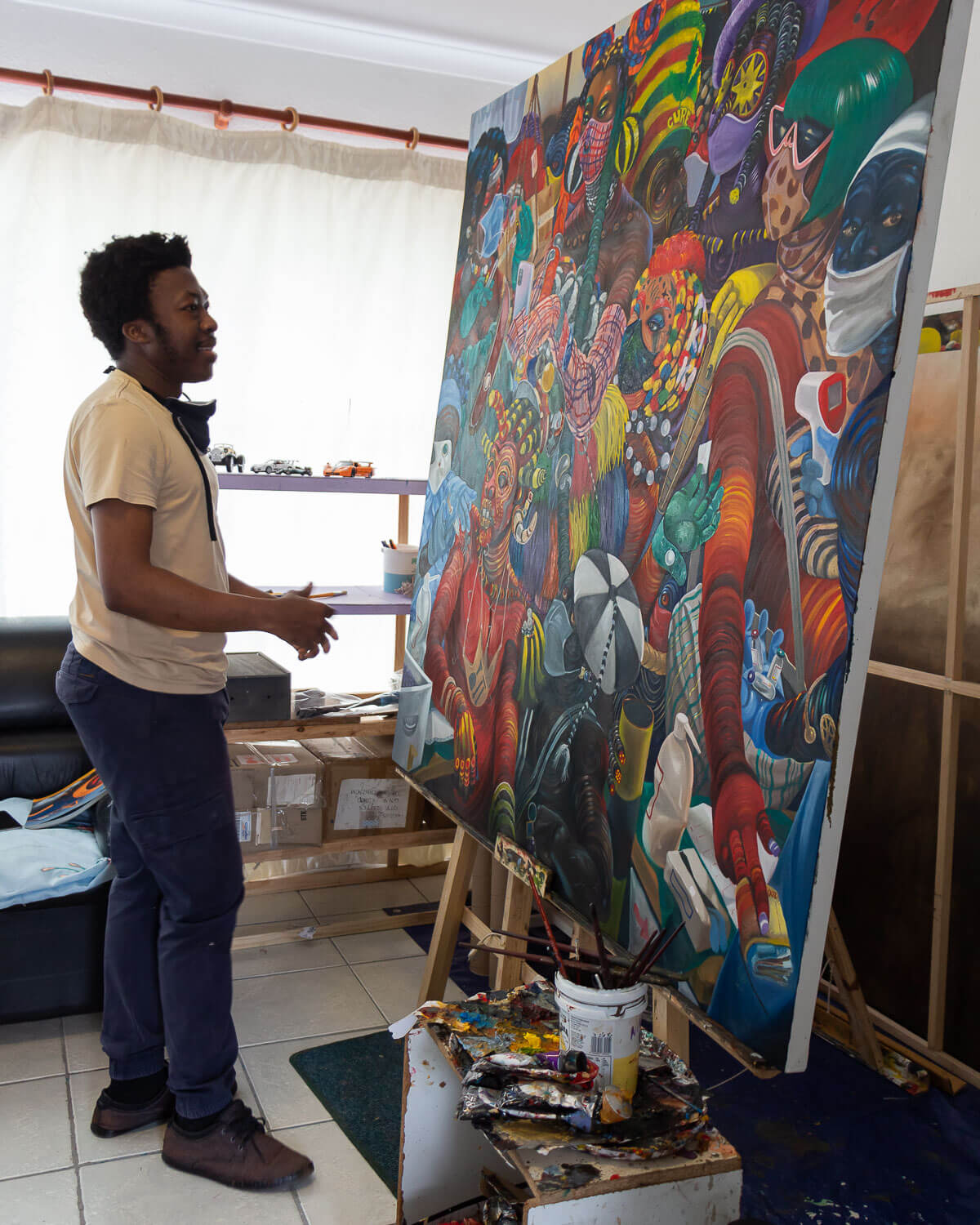 Kufa Makwavarara working beside a large colorful painting in his Cape Town studio, photographed for StateoftheART in 2021