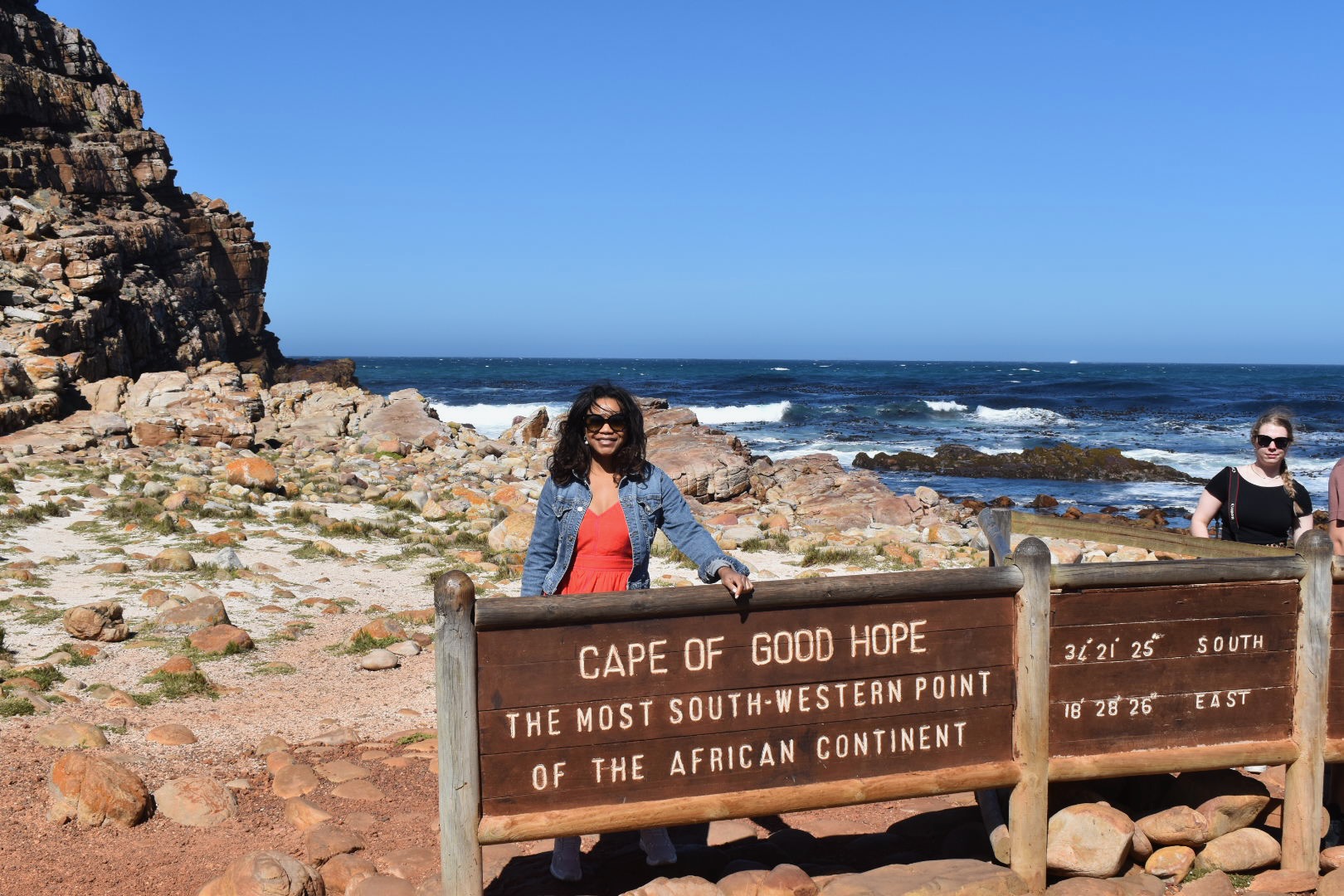 A traveler at the Cape of Good Hope sign beside the rocky ocean coastline