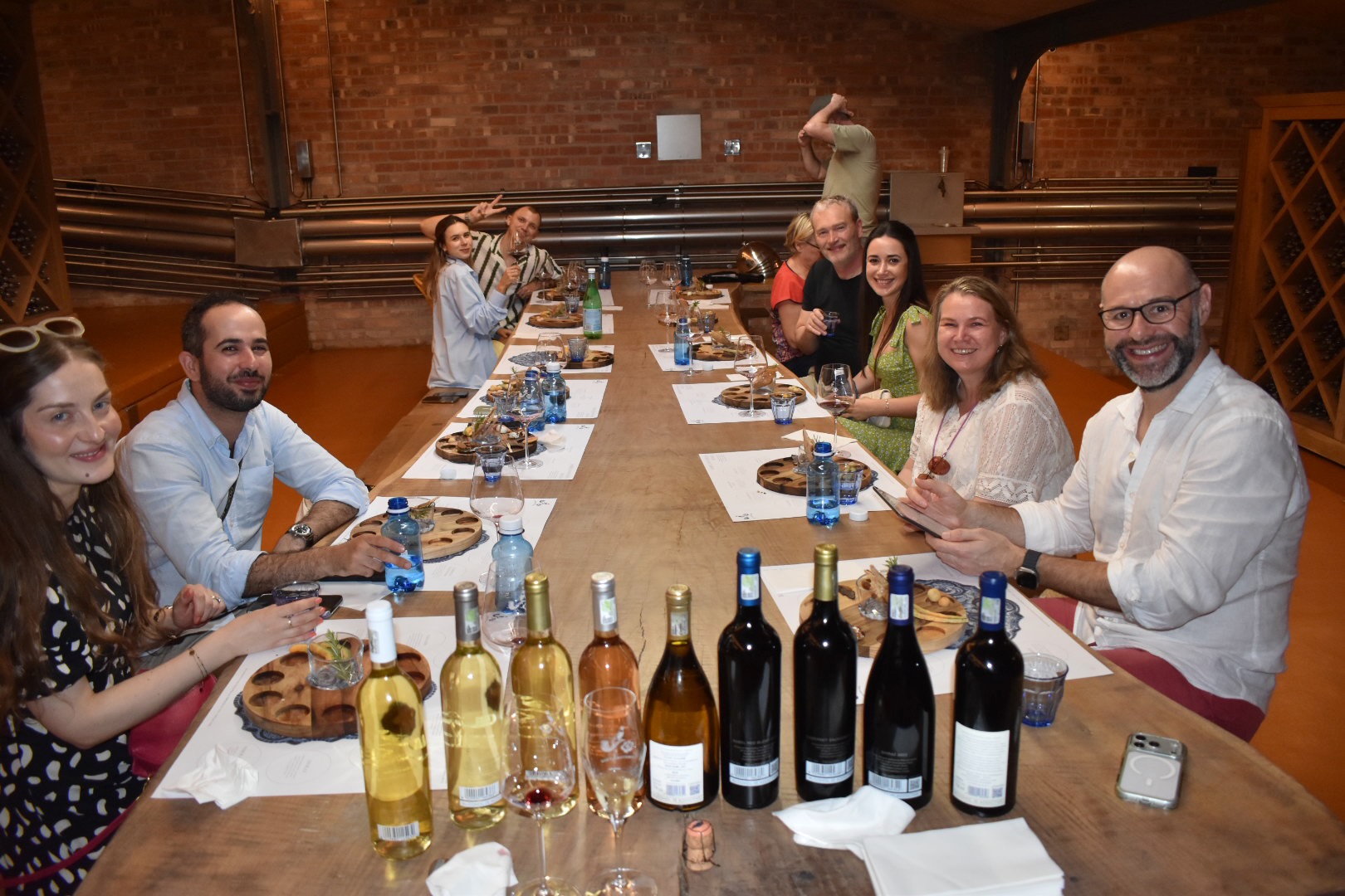 Travelers sharing a wine tasting around a long cellar table