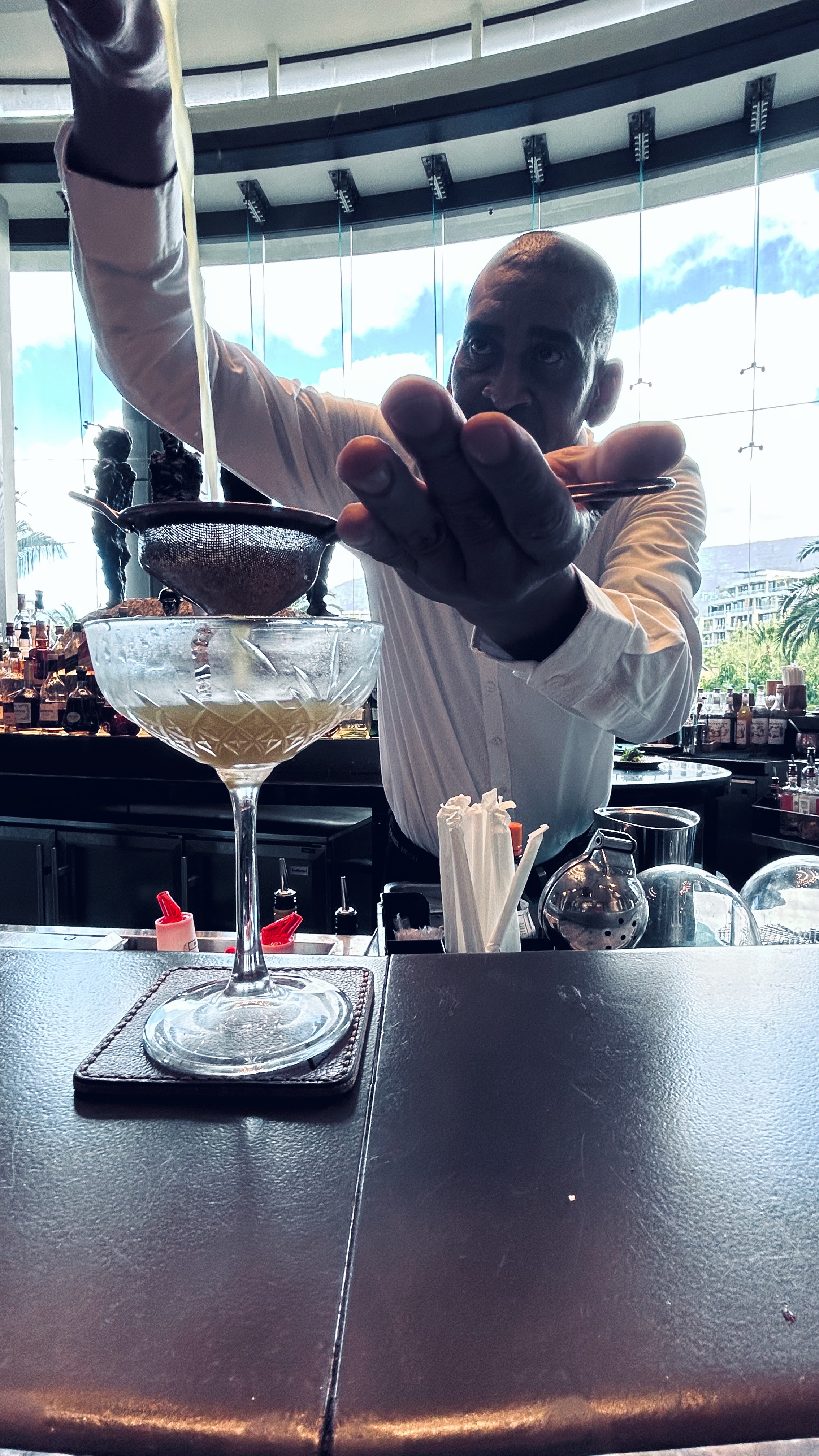 A bartender carefully straining a cocktail into a glass