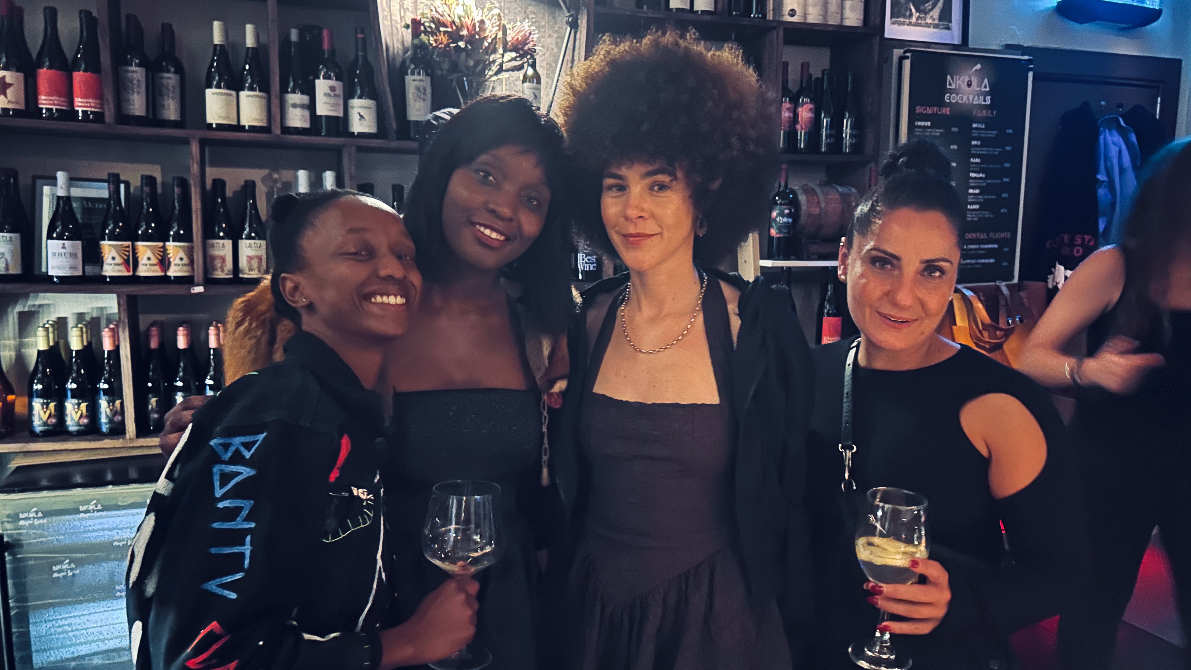 Four adults together at a wine bar with glasses in hand